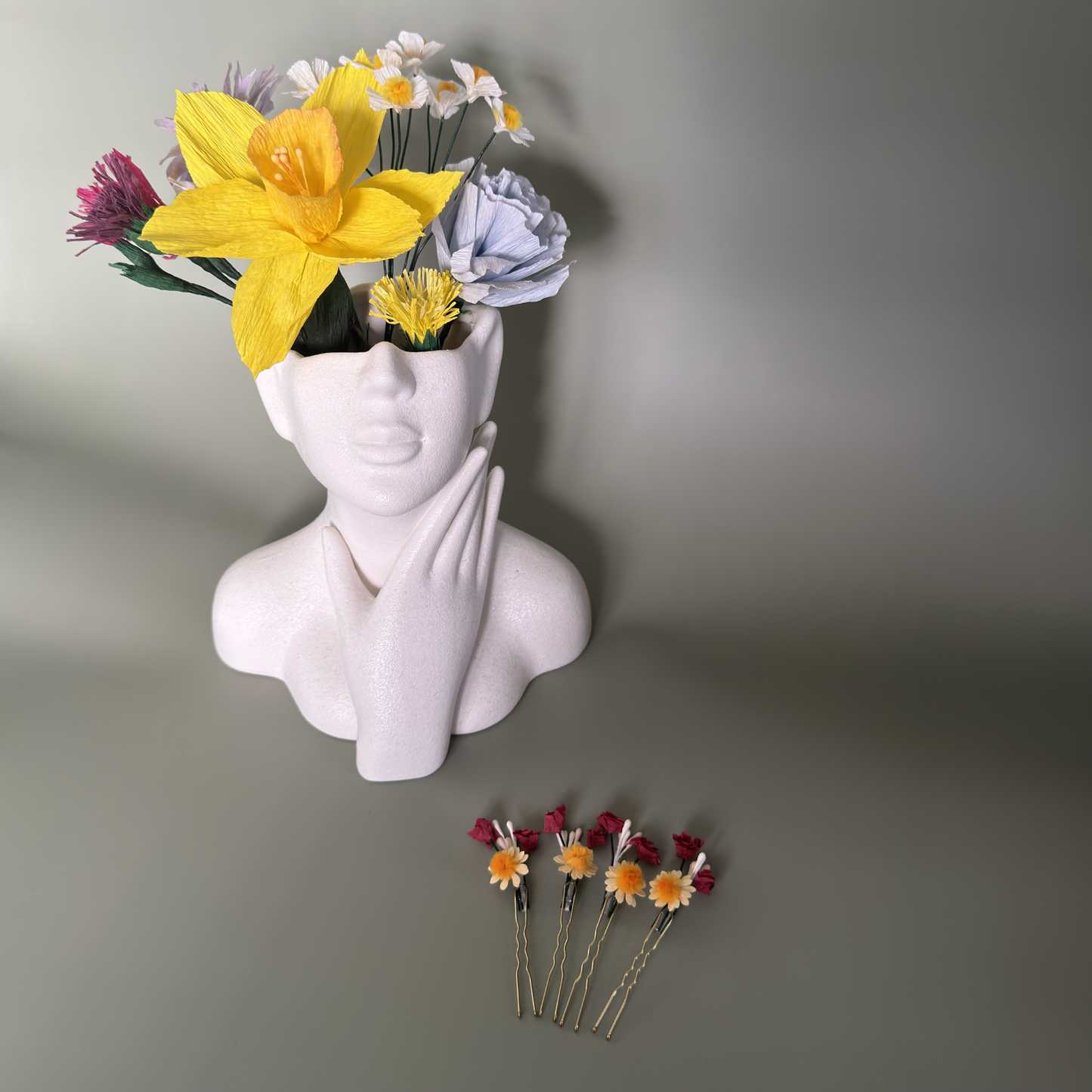 Haarnadeln Schleierkraut Gänseblümchen Krepppapier neben Papierblumen Büste